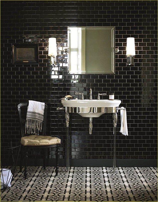 a bathroom with black and white tiles on the wall, sink and mirror in it