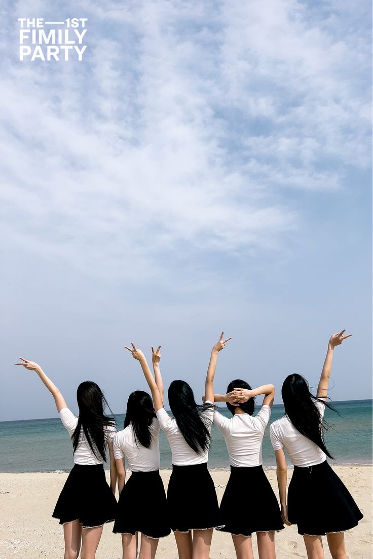 four young women standing on the beach with their arms in the air and one holding her head