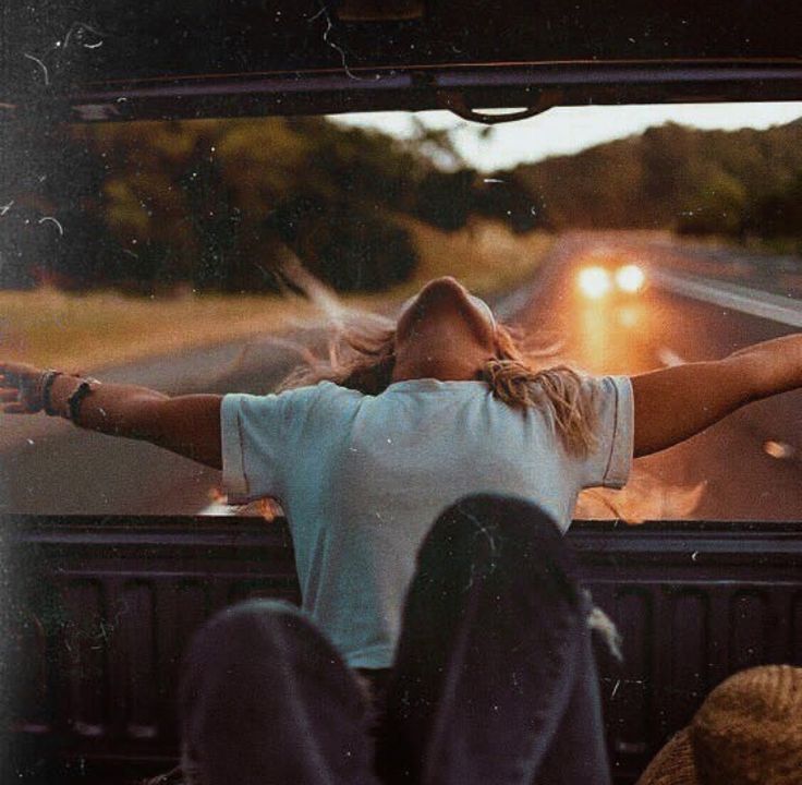 a woman sitting in the back of a truck with her arms outstretched