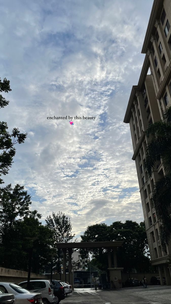 the sky is filled with clouds and there are cars parked on the street