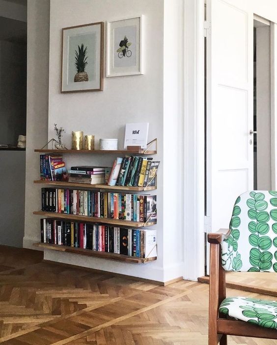 a room with a chair, bookshelf and pictures on the wall above it