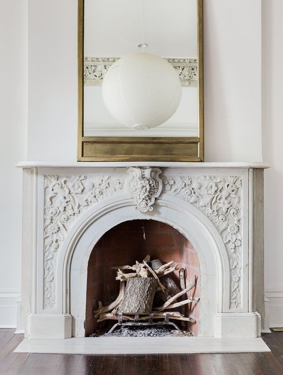 a white fireplace with a mirror above it