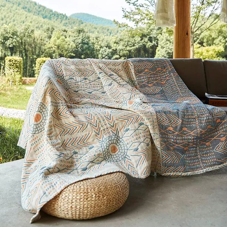 a couch covered with a blanket sitting on top of a cement floor next to a window