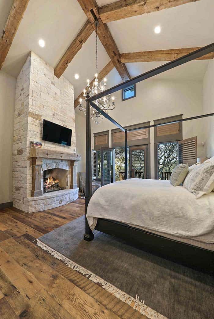 a bedroom with a bed, fireplace and tv on the wall next to wooden flooring