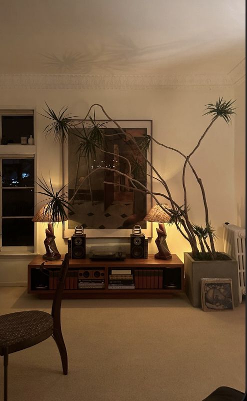 a living room filled with lots of furniture and plants on top of a wooden table