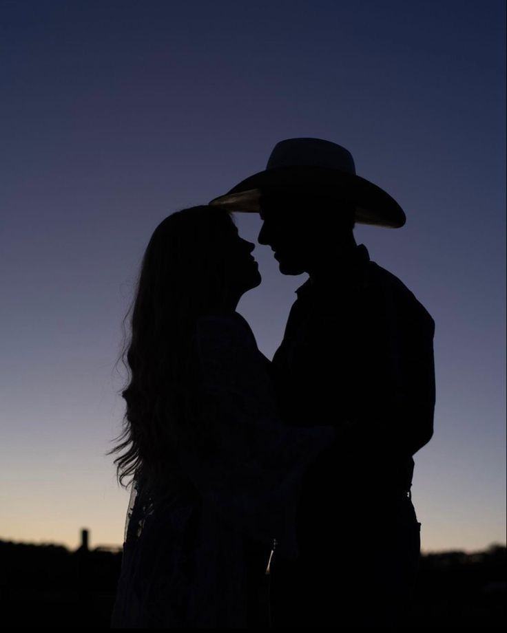 a couple standing next to each other in silhouette at sunset with the moon behind them