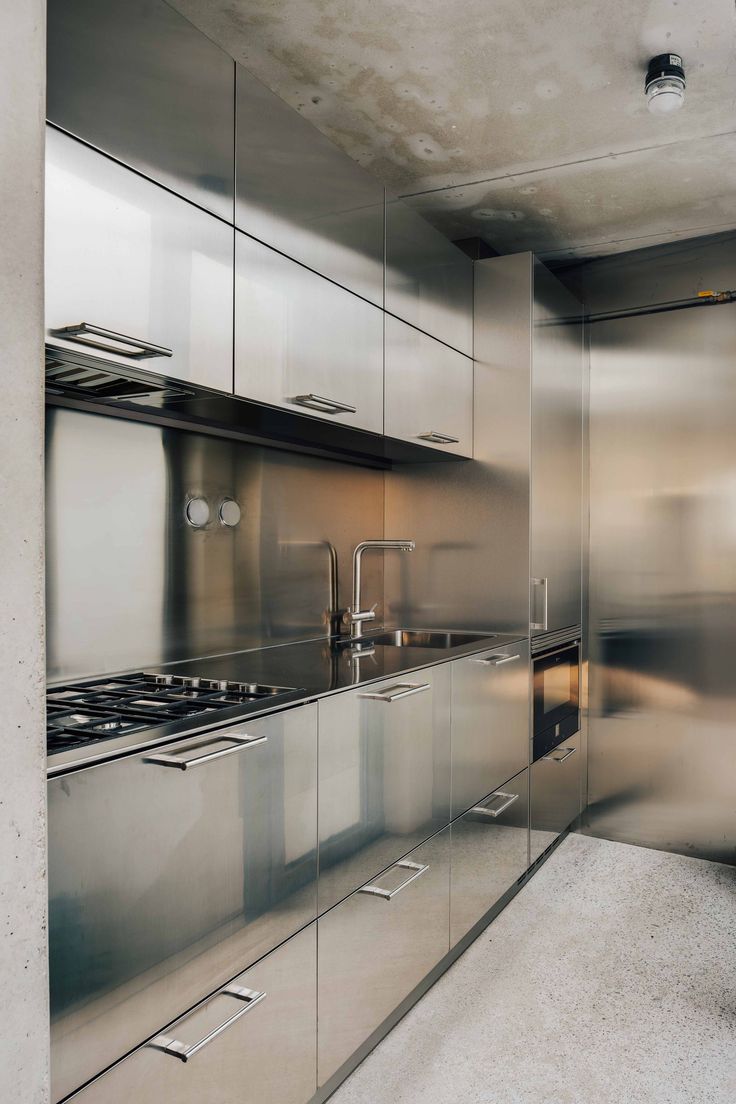 a metallic kitchen with stainless steel cabinets and counter tops, along with an oven in the center