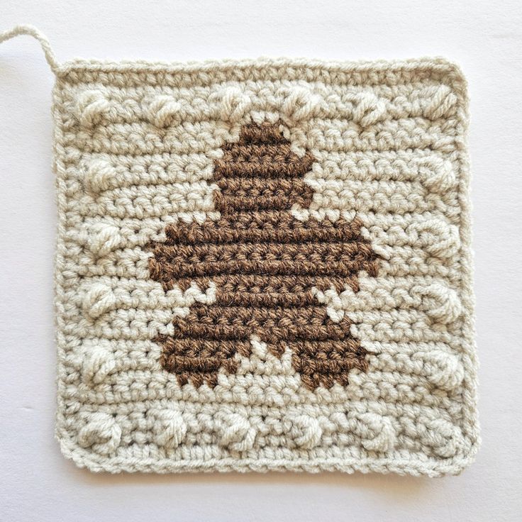 a crocheted square with a brown and white tree on it