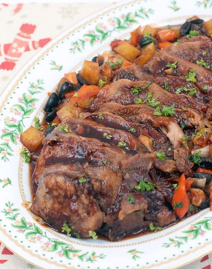 a plate with meat and vegetables on it sitting on a floral tablecloth covered table cloth