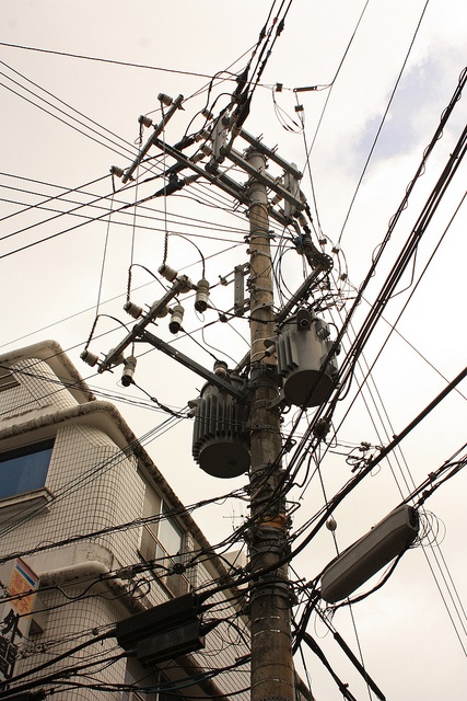 an electric pole with lots of wires and telephones on it in front of a building