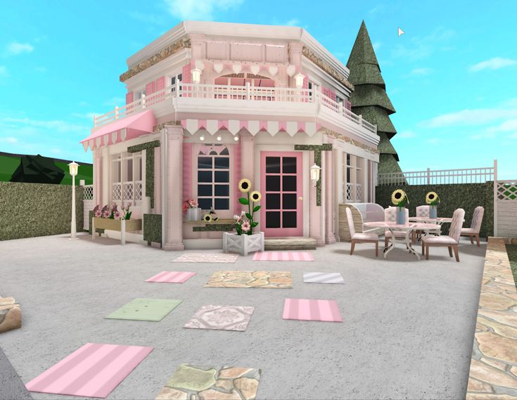 a pink house with lots of rugs on the ground and tables in front of it