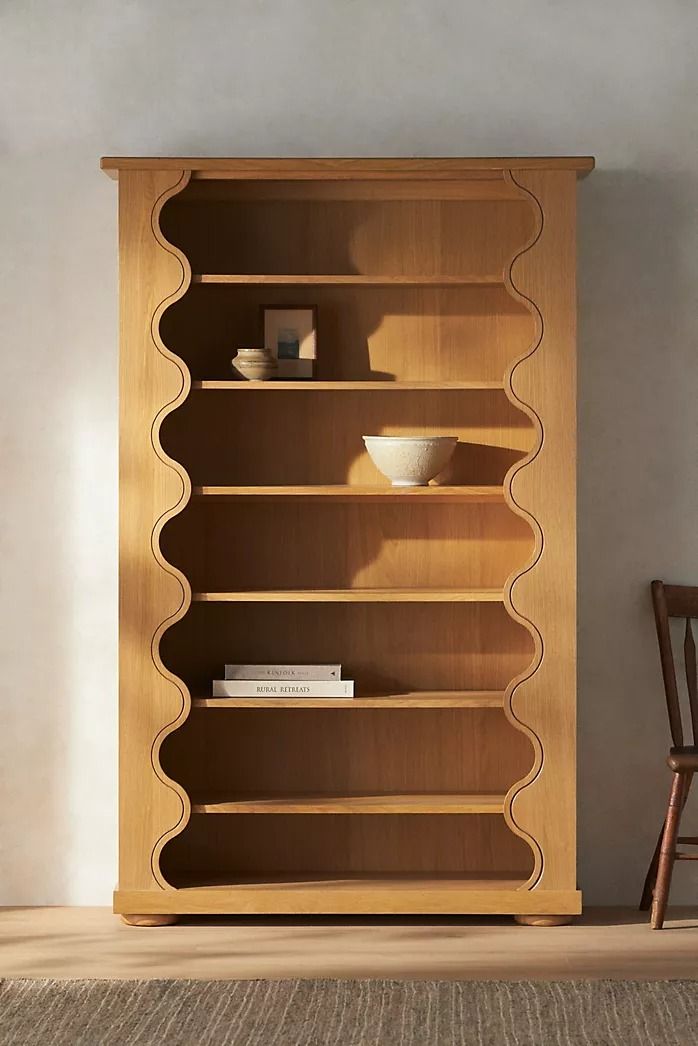 a wooden bookcase sitting on top of a carpeted floor next to a chair