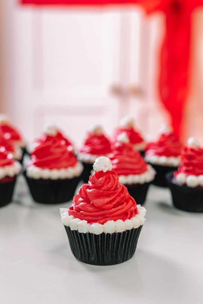 cupcakes with red frosting and white icing are arranged on a table