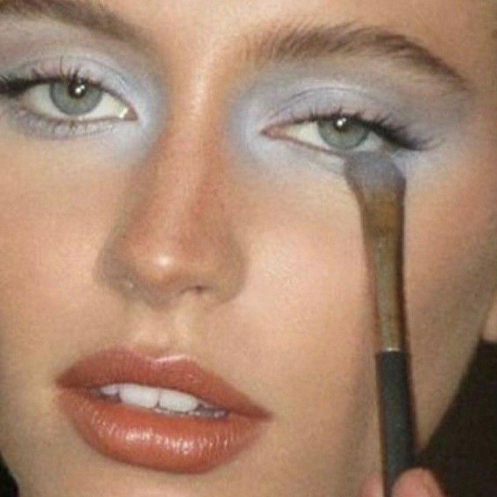 a close up of a woman with makeup brush