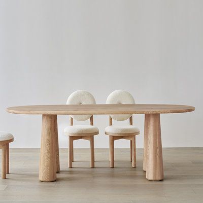 a wooden table with four chairs around it and a white wall in the back ground