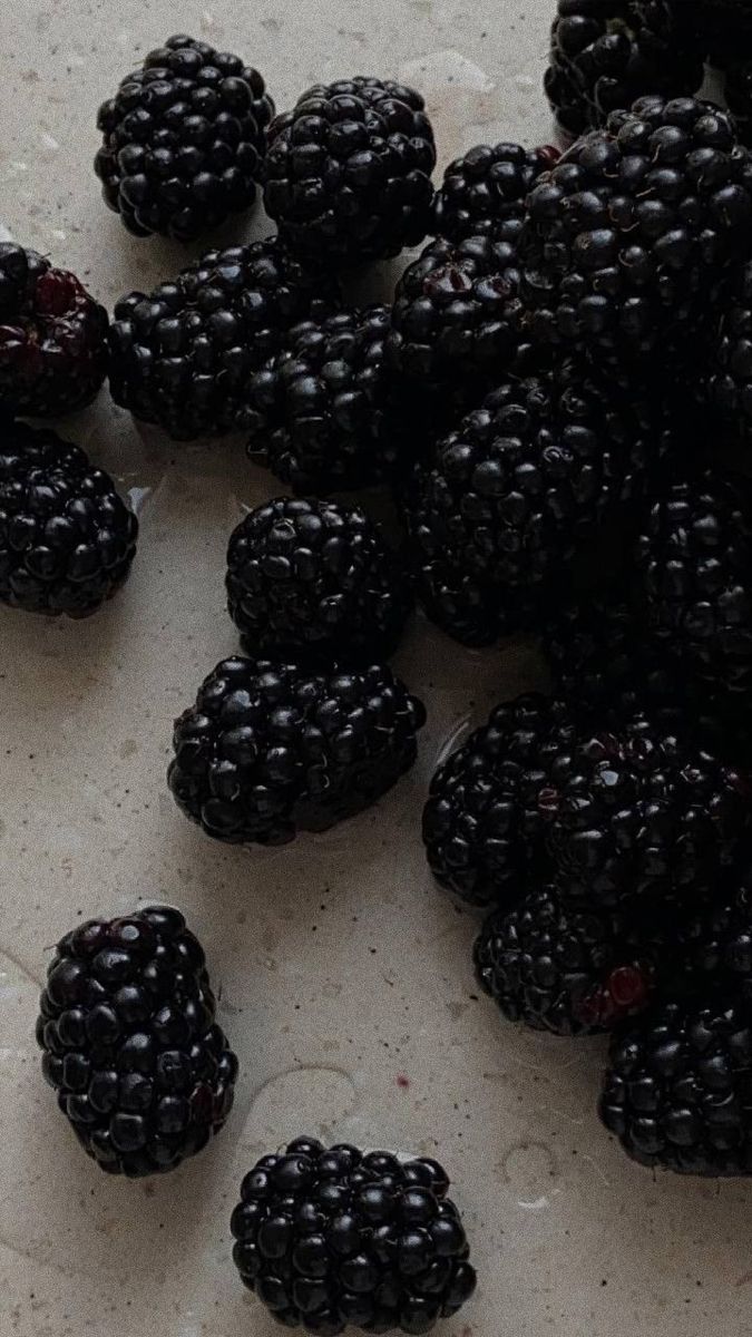 some blackberries are sitting on a white surface