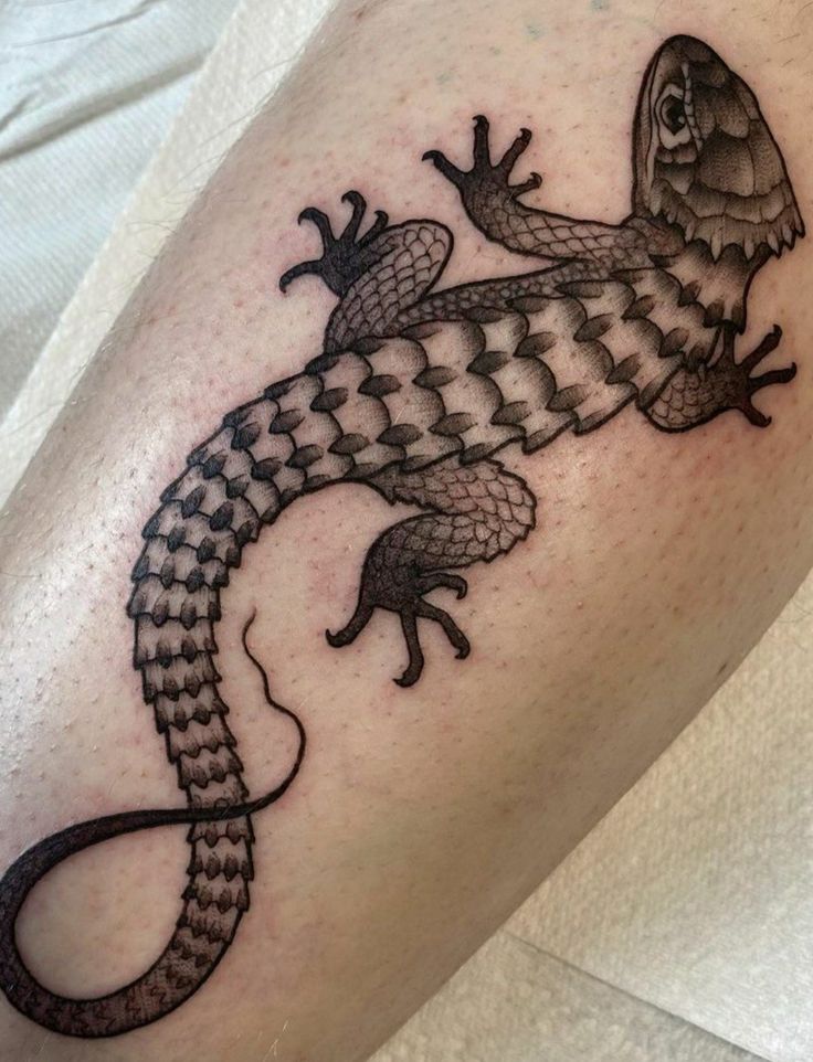 a lizard tattoo on the leg of a person's leg, it is black and white