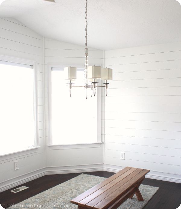 a wooden bench sitting in the middle of a living room next to a large window