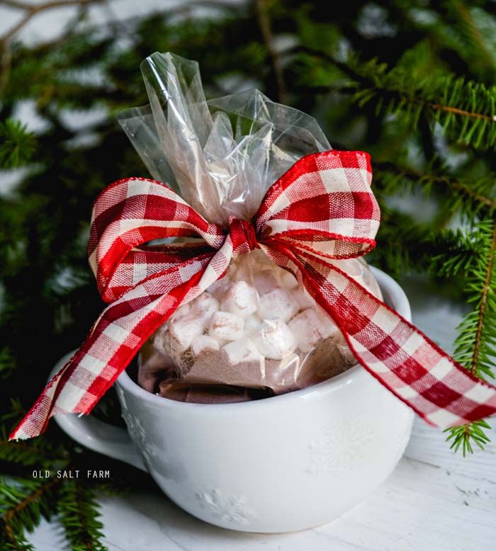 a cup filled with marshmallows wrapped in red and white ribbon