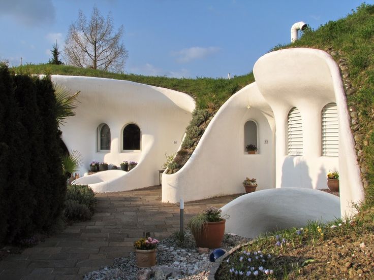 the house is shaped like a bird's nest and sits on top of a hill