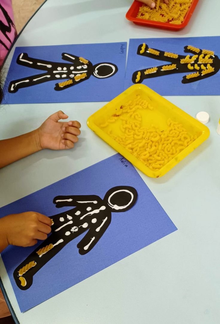 children are making their own paper cutouts at a table with blue and white mats