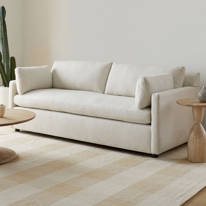 a white couch sitting on top of a wooden table next to a potted plant