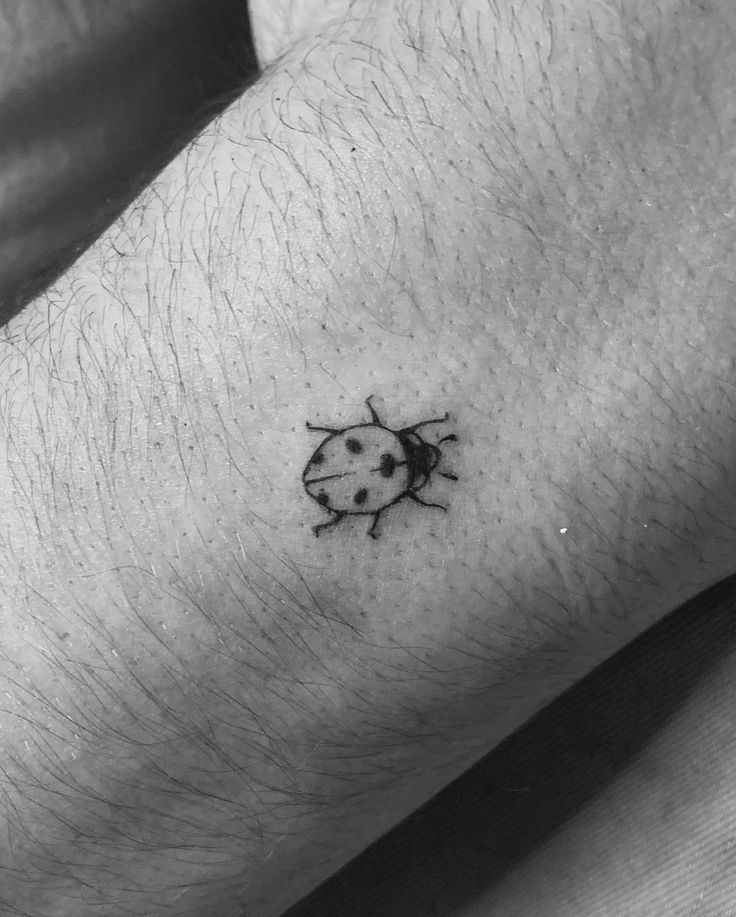 a small ladybug tattoo on the left wrist is shown in black and white