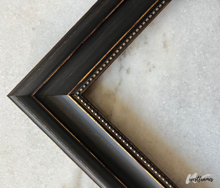 two black and gold framed pictures sitting on top of a white counter