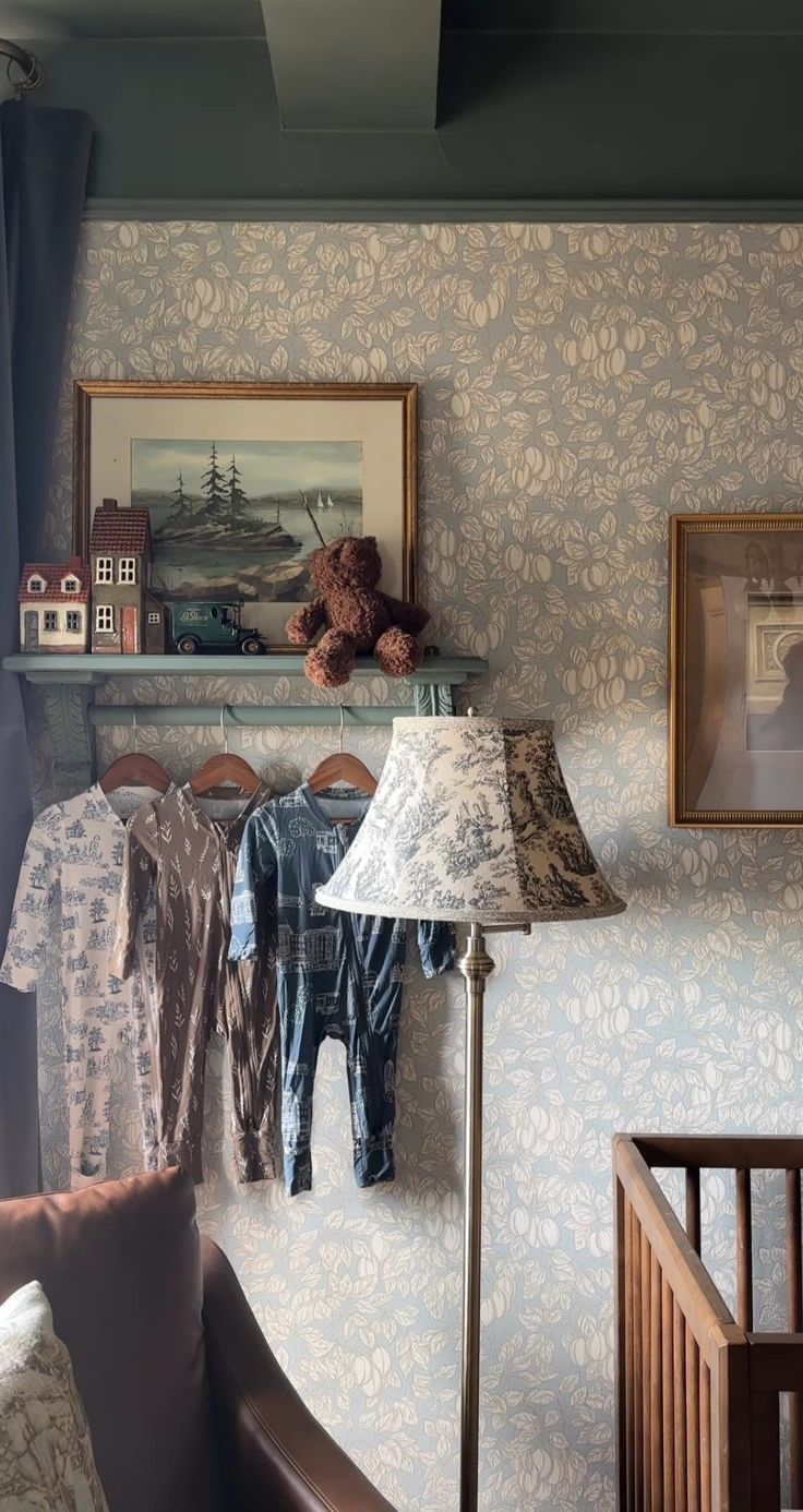 a baby's room with clothes hanging on the wall and a teddy bear sitting on a chair