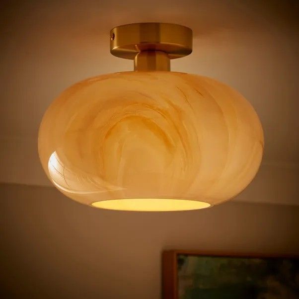 a close up of a light fixture in a room with a painting on the wall