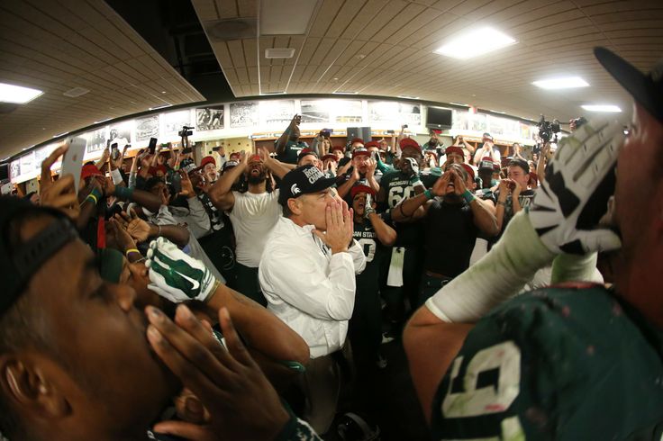 a group of football players sitting on the sidelines in a tunnel with their hands up