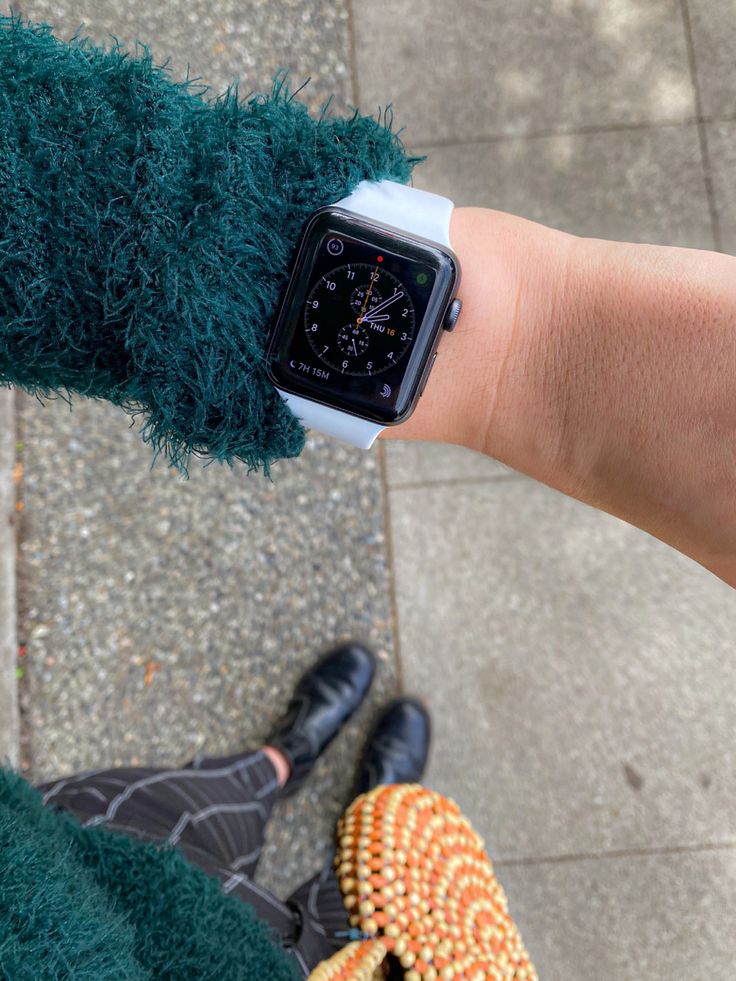 an apple watch on someone's wrist with some corn in the foreground and another person standing next to it