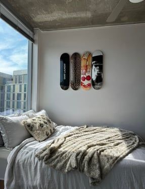 a bed with two skateboards mounted to the wall next to it and a window