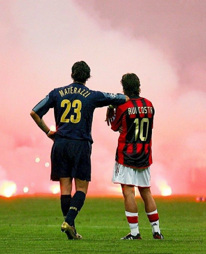 two soccer players are standing on the field as fireworks go off in the sky behind them