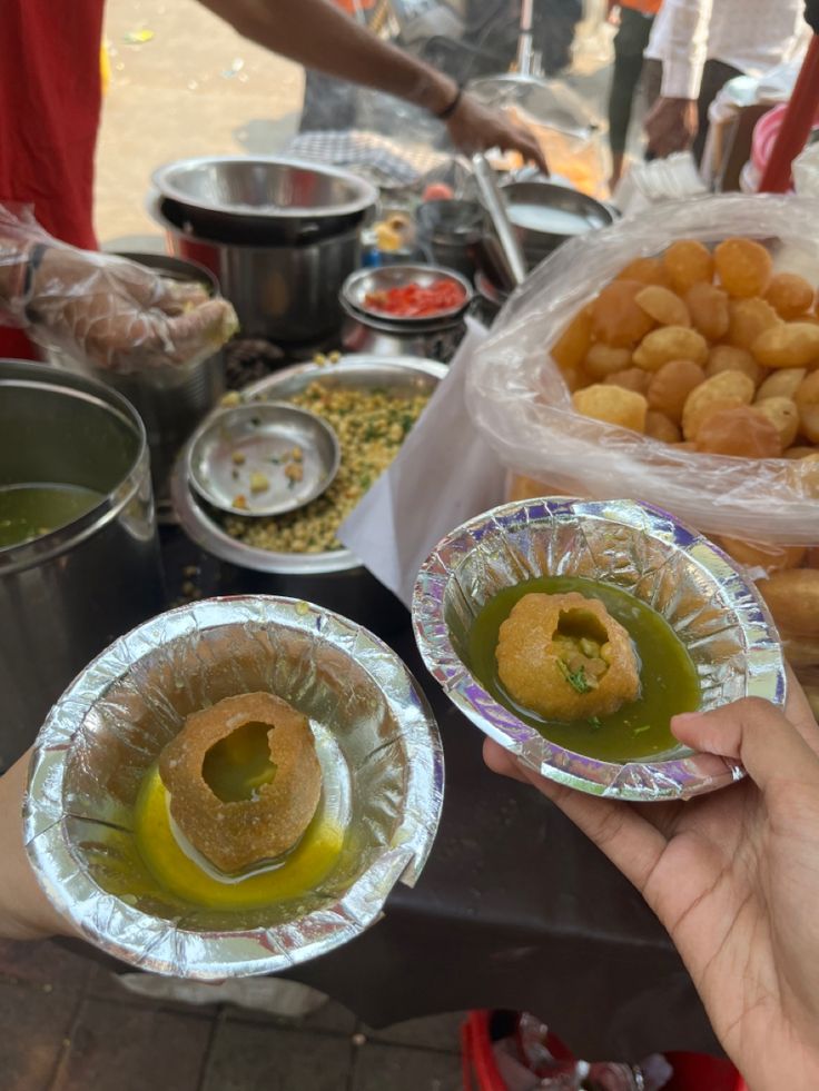 two people holding plates with food on them and some containers full of food in the background