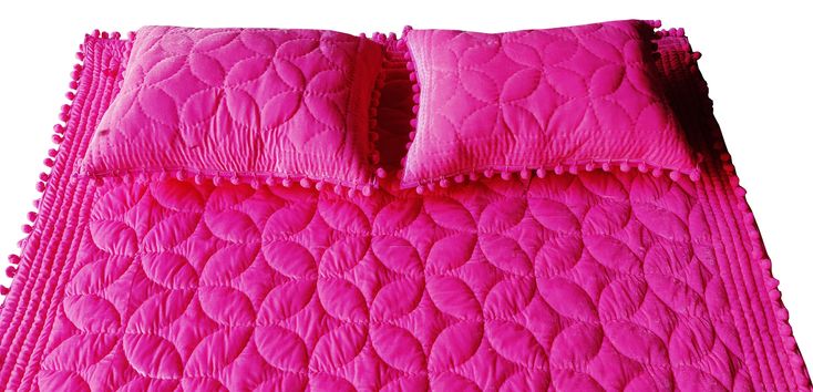 a bright pink quilted bed spread with ruffled edges