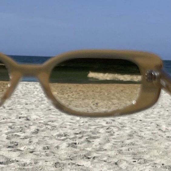 a pair of glasses sitting on top of a sandy beach