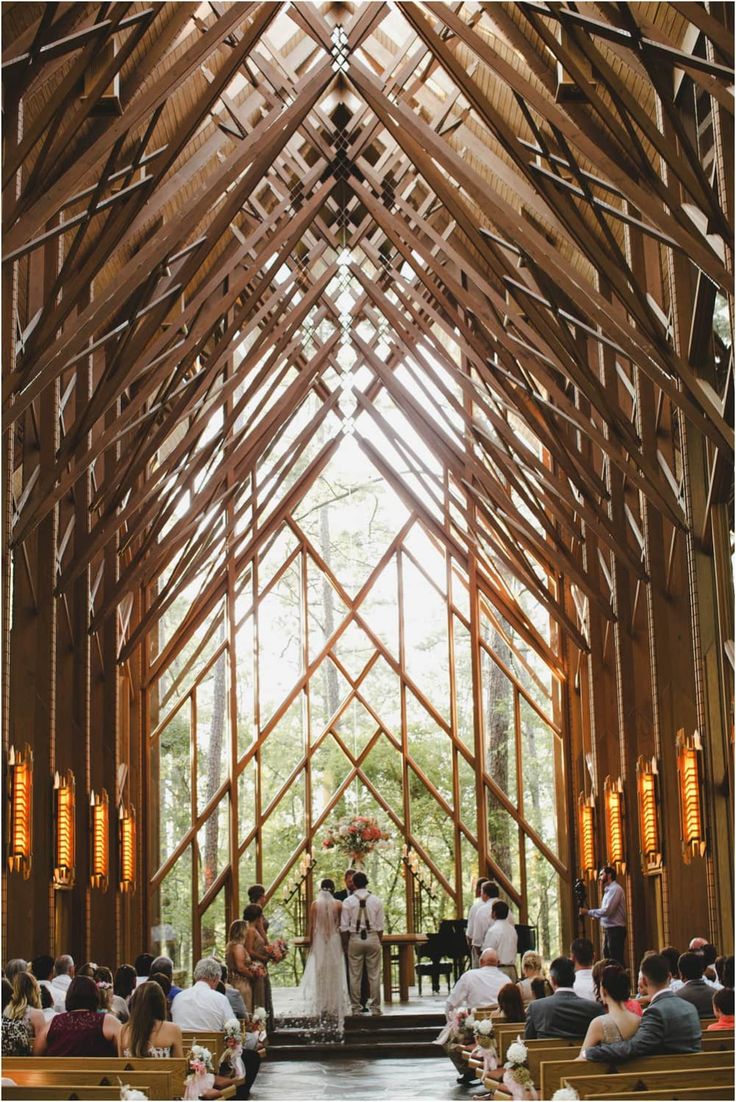 a bride and groom standing at the alter in front of their wedding party, surrounded by wooden beams