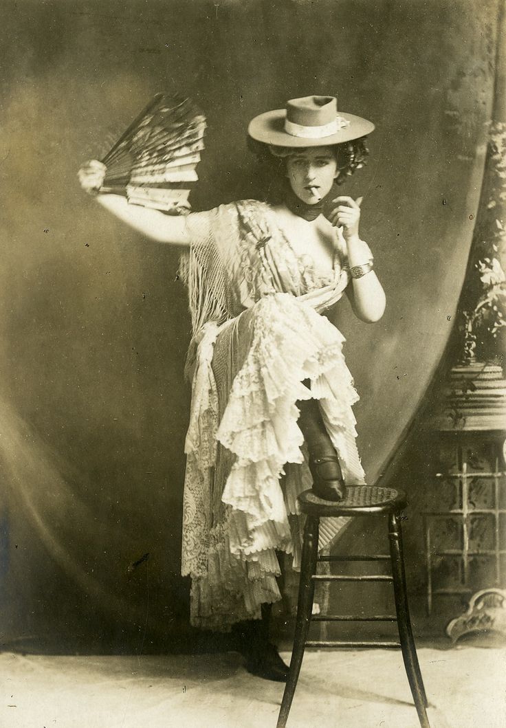 an old black and white photo of a woman with a hat on top of a chair