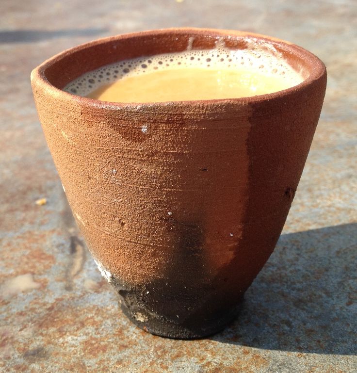 a brown cup sitting on top of a cement floor next to a window sill