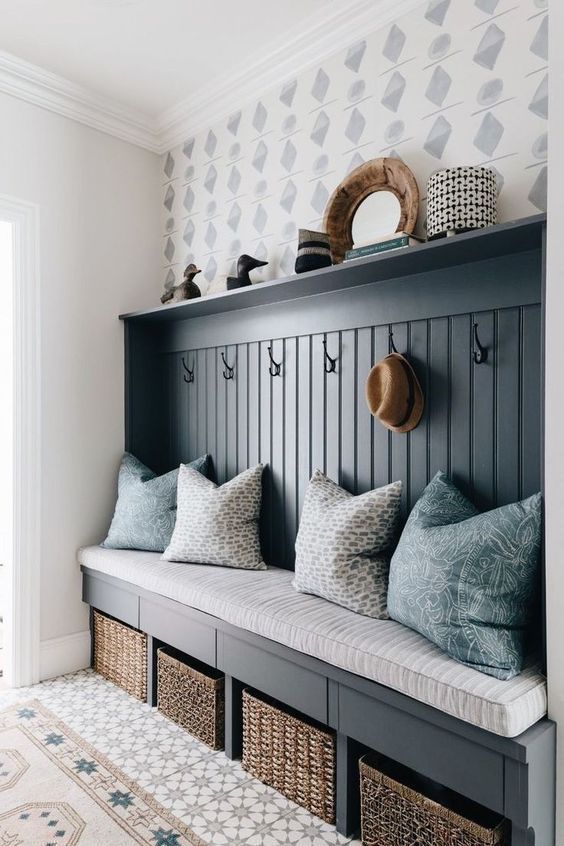 a bench with some pillows on top of it next to a wall mounted coat rack