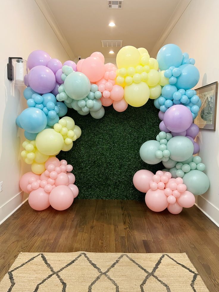 an arch made out of balloons in the shape of a heart on a wooden floor