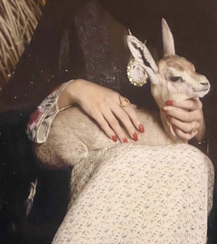 a woman holding an animal in her right hand and wearing jewelry on her left arm