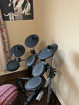 a drum set sitting on top of a hard wood floor next to a window with curtains