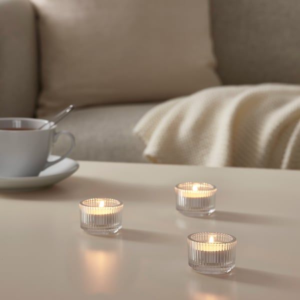 three tea lights sitting on top of a table next to a cup and saucer