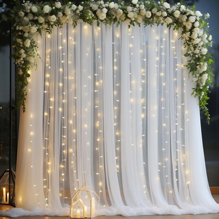 a white wedding backdrop with flowers and lights