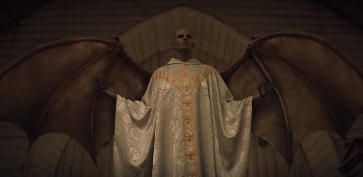 a man standing in front of a giant bat with his hands on his hips and wearing a priest's robe