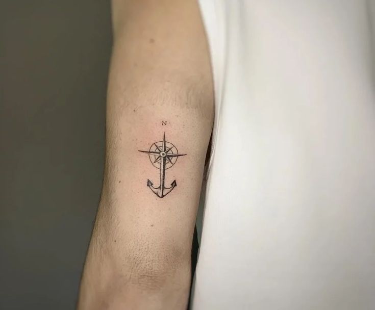 a person with a tattoo on their arm has a cross and an anchor in the middle