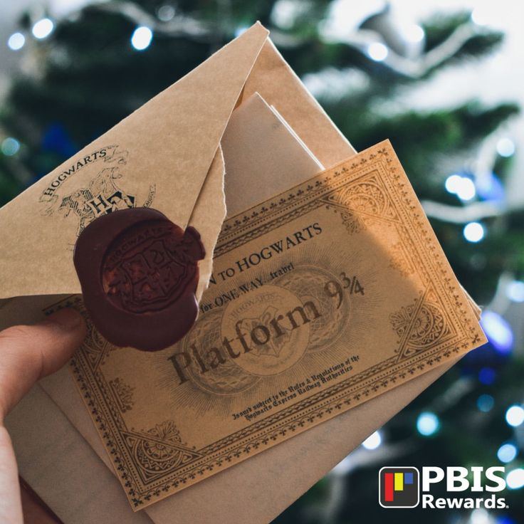 a person holding an envelope with a wax stamp on it in front of a christmas tree