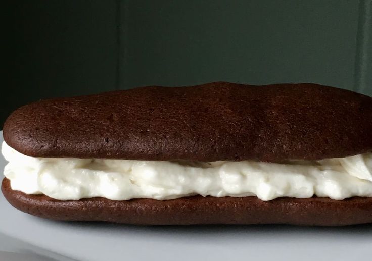 a chocolate sandwich with whipped cream on it is sitting on a white surface and green wall in the background